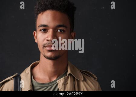 Image of masculine african american guy in coat posing and looking at camera isolated over black background Stock Photo