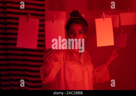 photographer on work, amateur, hobbyist or professional Young girl developing photos in a dark room. Retro style photography Stock Photo