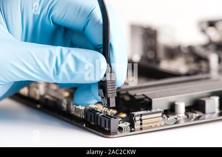 Connecting sata cable to motherboard of personal computer. Close-up. White background. Stock Photo
