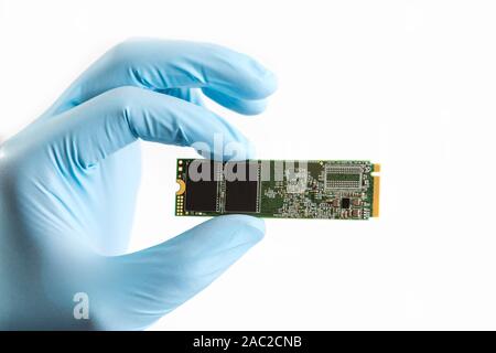 Master hand in blue glove holds ssd disk hard drive on white background. M2 SSD disk for data storage at high speed, isolated on white background. Clo Stock Photo