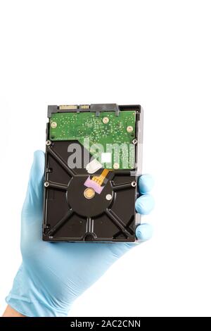 Repairman hand in blue runnber glove holds computer hard drive disk with green chip. white background. Stock Photo