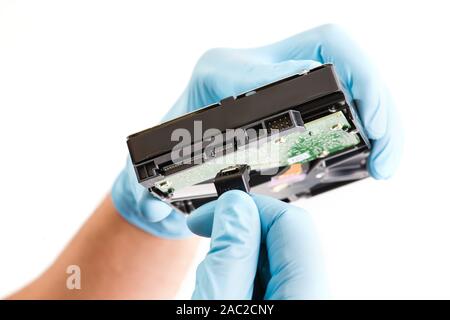 Repairman hand in blue runnber glove holds computer hard drive disk with green chip. Stock Photo