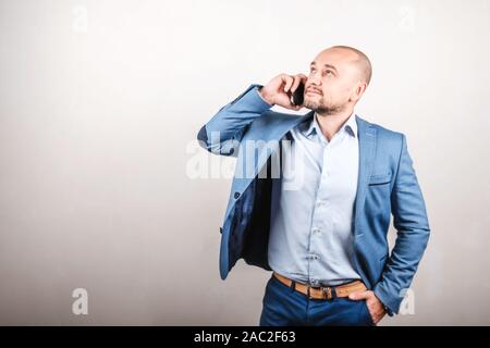Business man in a jacket talking on the phone. A man on a gray background. Communication concept Stock Photo