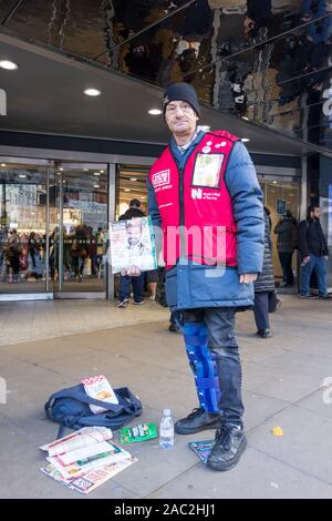 Big Issue seller outside John Lewis on London's Oxford Street Stock Photo