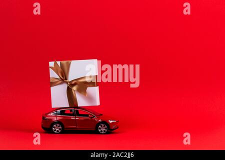 Red toy model car with present gift box on the top, red background Stock Photo