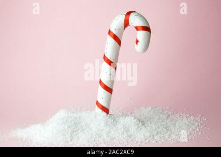 Christmas candy in snow isolated on pink. Minimal sweet food holiday creative concept. Stock Photo