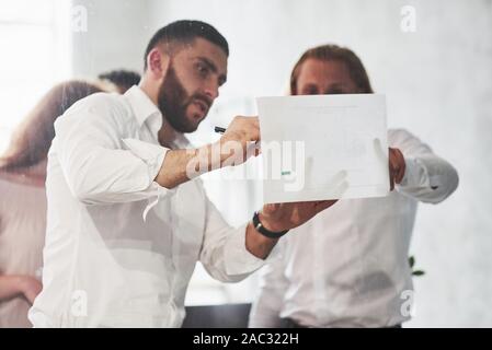 Making corrections. People working in the office and discuss some business details using information on paper Stock Photo