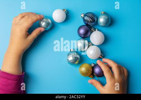 children's pens play with multi-colored Christmas toys on a blue background. Stock Photo