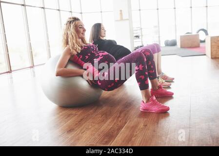 Side photo of two pregnant women doing fitness exersices using stability balls Stock Photo