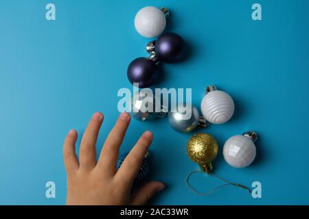 children's pens play with multi-colored Christmas toys on a blue background. Stock Photo