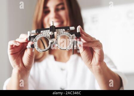Focused photo. Female doctor showing the little phoropter by holding it in two hands Stock Photo