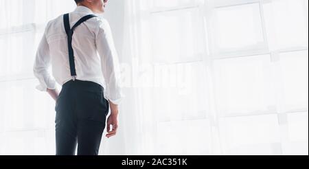 Back view of the businessman in classic wear looking through the windows Stock Photo