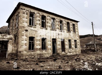 Abandoned house with stucco architraves in Caucasus mauntais like a crumbling old thing Stock Photo