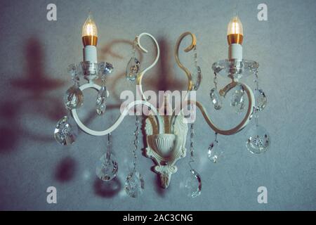 Stylish lamp on the wallpaper . Wall light of gilded metal with two electric candles . vintage wall lamp isolated on white with clipping path Stock Photo