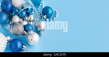 Christmas baubles in a wine glass on a light blue background close up Stock Photo