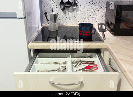 Open drawer in a modern kitchen, with a kettle and a coffee maker on the hob Stock Photo