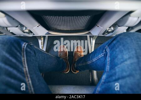 Legroom between seats in commercial airplane. Personal perspective of passenger on leg in economy class. Stock Photo