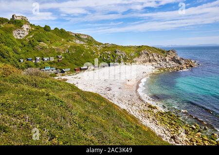 Secluded shingle beach and beach huts of Church Ope Cove on the coast of the Isle of Portland in Dorset UK Stock Photo