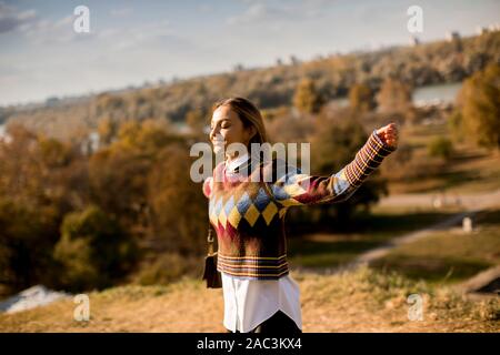 Pretty young woman walking outside at sunny autumn day