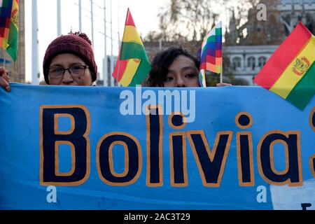 Protesters hold a banner, Bolivian and Wiphala flags during the rally.People gathered outside Downing Street to raise their voices against the coup in Bolivia and show their support to ousted president Evo Morales. Morales won the past elections for a run his four consecutive periods as a president, but the opposition claimed that there was a fraud. Morales has to quit and is in exile in Mexico after the Army and Police chief suggested that Morales should abandon the presidency. Stock Photo