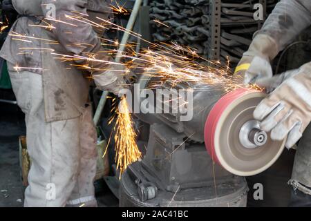 Two blacksmiths works by hand in blacksmith shop. Iron grinding Stock Photo