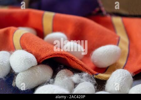 Silk fabric pongee orange color and silk cocoons Stock Photo