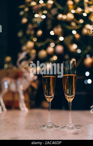 Two glasses of champagne standing on the blurred decorated christmas tree background. Stock Photo