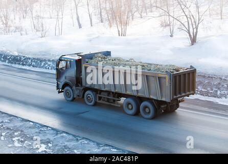 big dump truck goes on highway in winter Stock Photo