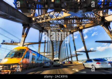 Motor vehicles and railway train traffic on Sydney Harbour bridge in motion inside massive steel arch of multi-lane transport connection in Sydney. Stock Photo