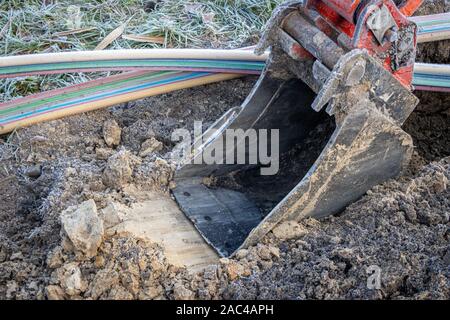 an excavator digging a trench to lay a high-speed Internet DSL cable Stock Photo