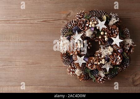 Christmas wreath decorated with pine and fir tree cones on wooden door Stock Photo