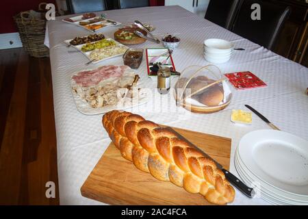 Freshly backed cob of bread and assorted col meats and pickles on the dining room table Stock Photo
