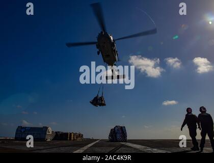 191126-N-LK322-1148 PACIFIC OCEAN (Nov. 26, 2019) An MH-60S Seahawk, assigned to the “Eightballers” of Helicopter Sea Combat Squadron (HSC) 8, lowers cargo onto the flight deck during a vertical replenishment aboard the aircraft carrier USS Theodore Roosevelt (CVN 71) Nov. 26, 2019. Theodore Roosevelt is underway conducting routine training in the Eastern Pacific Ocean. (U.S. Navy photo by Airman D.J. Schwartz) Stock Photo