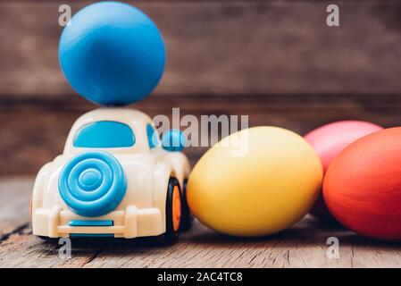 Easter egg and toy car on wooden background, happy easter day concept Stock Photo