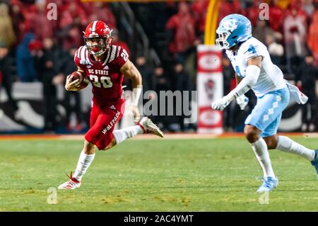 Raleigh, North Carolina, USA. 30th Nov, 2019. Nov. 30, 2019 - Raleigh, North Carolina, USA - North Carolina State Wolfpack running back Jordan Houston (20) eludes North Carolina Tar Heels defensive back Trey Morrison (4) during Saturday's game between the NC State Wolfpack and University of North Carolina Tar Heels. The Tar Heels defeated the Wolfpack, 41-10. Credit: Timothy L. Hale/ZUMA Wire/Alamy Live News Stock Photo