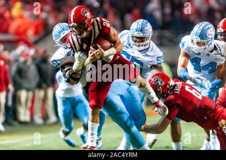 Raleigh, North Carolina, USA. 30th Nov, 2019. Nov. 30, 2019 - Raleigh, North Carolina, USA - North Carolina State Wolfpack running back Jordan Houston (20) is thrown to the ground by North Carolina Tar Heels defensive lineman Raymond Vohasek (51) during Saturday's game between the NC State Wolfpack and University of North Carolina Tar Heels. The Tar Heels defeated the Wolfpack, 41-10. Credit: Timothy L. Hale/ZUMA Wire/Alamy Live News Stock Photo