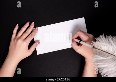 Female hands writing on white paper with feather vitage pen Stock Photo