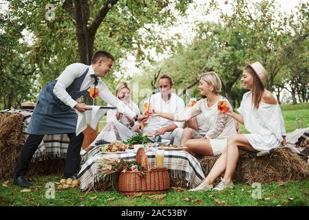 Even waiter have a good time during the service with these beautiful group of friends Stock Photo