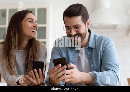 Cheerful laughing couple using smartphones play mobile games together Stock Photo