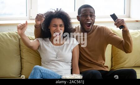 Excited biracial couple have fun watching sports game together Stock Photo