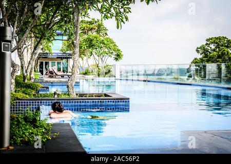 rooftop infinity swimming pool with sunbathing lounge chairs and trees
