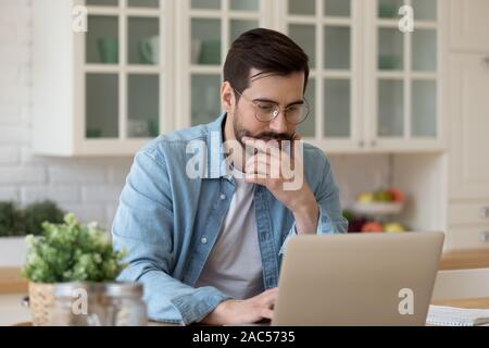 Young guy using laptop notebook sit at home table Stock Photo
