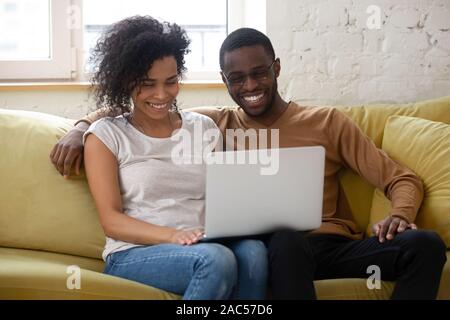 Happy biracial couple have fun watching video on laptop Stock Photo