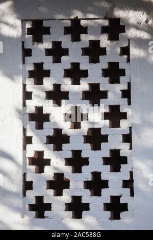 window on the wall of the shed with vents made of bricks in the shape of a cross Stock Photo