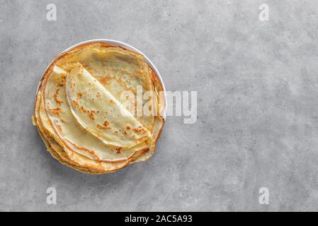 Crepes (Blini) on light grey background, top view, copy space. Homemade thin crepes for breakfast or dessert. Stock Photo