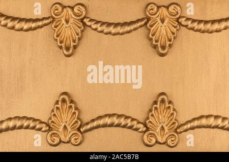 Luxury frame made of golden stucco plaster lying on golden surface. Text place, copy space. Top view. Fashion background Stock Photo