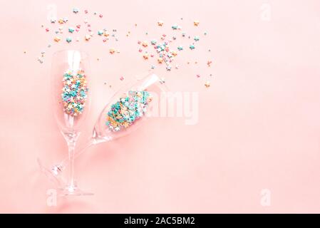 Champagne glasses with colorful sugar sprinkles on pink background. Holiday, party and celebration concept. Creative flat lay with copy space. Stock Photo