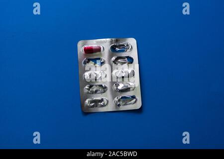 The last medicine pill on a blue background. Treatment of diseases. Stock Photo