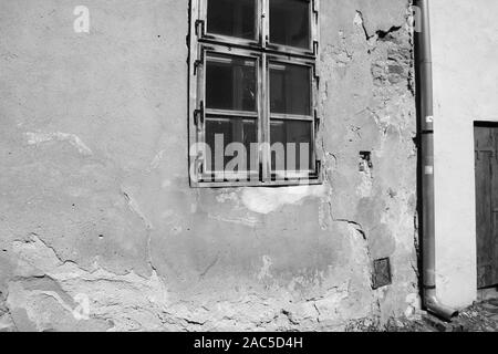 View of an old house with cracks on the wall and window, black and white photo
