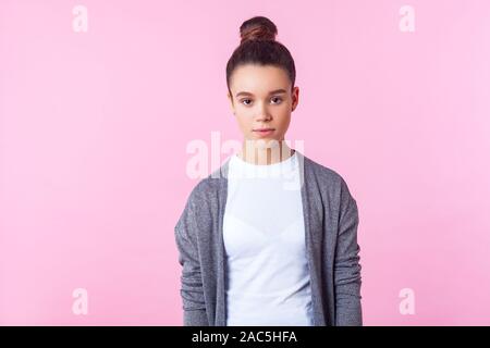 Portrait of cute brunette teenage girl with bun hairstyle in casual pullover and T-shirt looking with serious expression, clean fresh face skin, natur Stock Photo